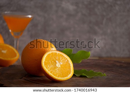            The yellow oranges that are laid on the brown wooden floor have a cemented backdrop.                    