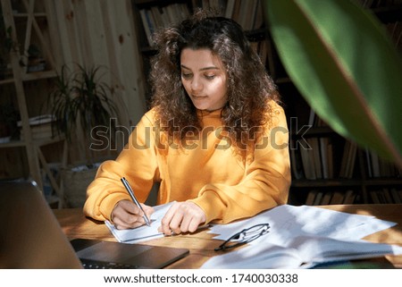 Hispanic teen girl college student study from home office making notes doing homework in sunny room. Latin smart teenage school pupil learning online on laptop sit at desk. Distance elearning concept. Royalty-Free Stock Photo #1740030338