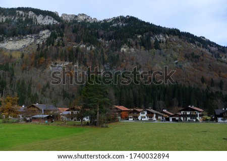 Picture of small village located next to the valley, with greenery and woods surrounding it. 