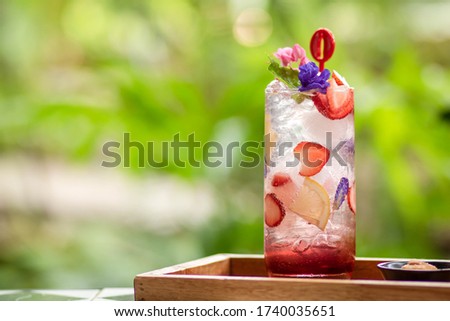 Ice with sweet water topped with Fresh pink lemonade with raspberries decorated with mint leaves, orange suitable for summer. Strawberry mojito cocktail. a green natural background. candy summer .