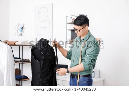 Young male Asian stylist near mannequin in studio
