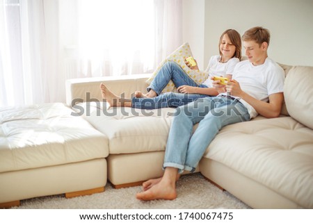 Teenagers play a game on the phone at home while sitting on the couch.