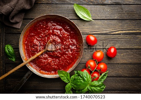Classic homemade Italian tomato sauce with basil for pasta and pizza in the pan on wooden background, top view. Royalty-Free Stock Photo #1740070523