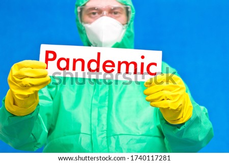 Medical worker holding a white poster with the inscription pandemic, standing on a blue background.