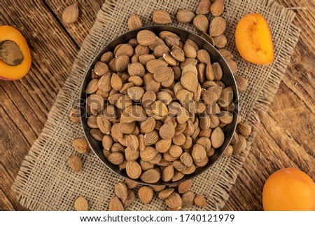 Vintage wooden table with a portion of shelled Apricot Kernels (close up shot; selective focus)