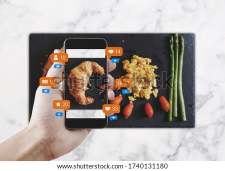 Taking food photograph by mobile smart phone, and sharing on social media, social network with notification icons