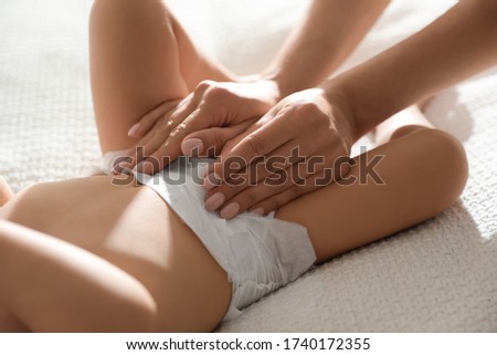 Mother changing baby's diaper on bed at home, closeup