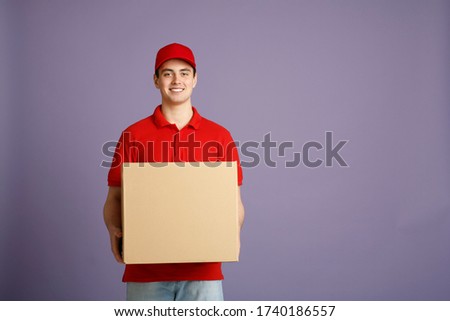 Fast delivery and big parcel. Caucasian post worker gives out big box, isolated on gray background, studio shot
