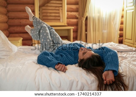 Young woman wearing warm sweater on bed at home