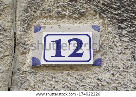 Number twelve on a plate on a wall, detail of a number of information in a house in the city