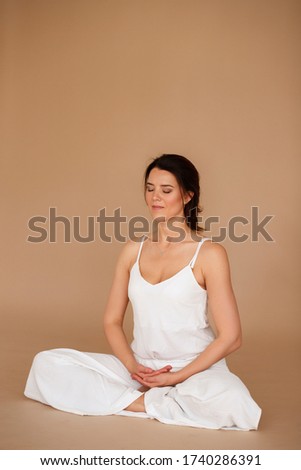 woman in white clothes in lotus position on a brown background. yoga day. morning meditation