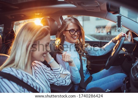 Two female friends enjoying road trip traveling at vacation in the car