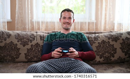 A man sits on the couch and plays the prefix at home