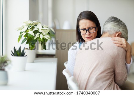 Portrait of crying female doctor hugging senior woman while trying to comfort her after bad news, copy space