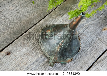 Antique brass funnel with handle on wooden background. Copy space for text, photography props. 