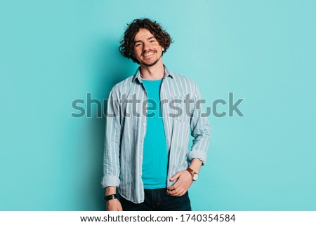 Young cheerful positive man isolated over blue background. Guy stand alone in studio and smile. Stylish modern fashionable man on picture