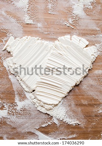 Amorous cook made heart from the flour on a cutting board