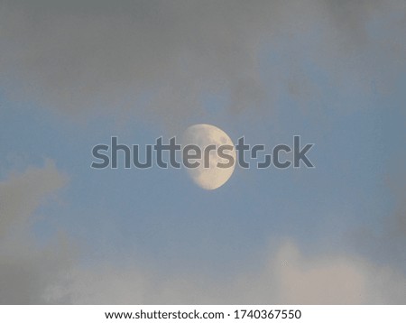 Big full silver golden moon against clouds in light sky