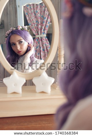 girl with violet hair looks in the mirror