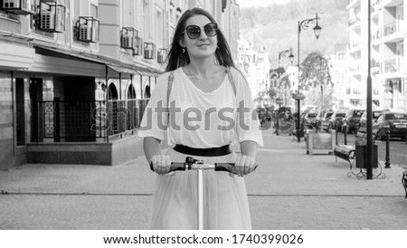 Portrait of beautiful young woman commuting to work on electric scooter.