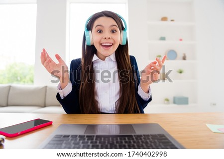 Photo of little pupil student lady talk skype notebook online lesson video call september sit desk use earphones distance glad to see classmates quarantine study living room indoors