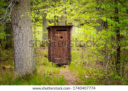 beautiful wooden professionally repaired outhouse in a green forest serves as a toilet in nature Royalty-Free Stock Photo #1740407774
