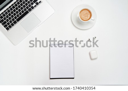 laptop, Notepad with pen and wireless headphones, on a white background. View from the top. Minimal workspace