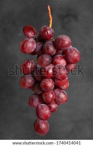Flying food - Bunch of red grapes besides concrete background.  