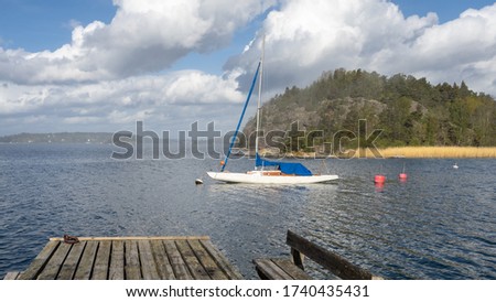Morning fog. Panoramic view of Baltic sea bay with sailing yacht. Stockholm Archipelago. Horizon. Green forest  islands. Blue sky and white clouds.  Rocky sea shore of Scandinavia. Wooden pier bench.