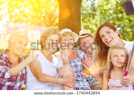 Extended family with grandparents and child using selfie stick while taking pictures