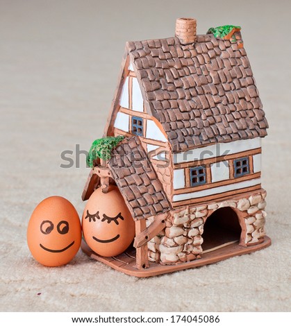 two funny smiling eggs near a house.