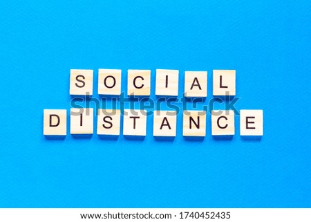 Words social distance. Wooden inscription on a blue background. Information sign of social distance from blocks on a blue background.