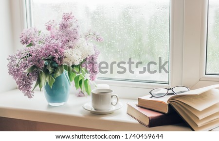 Bouquet of lilacs in a vase,cup of coffee and books on the windowsill. Royalty-Free Stock Photo #1740459644