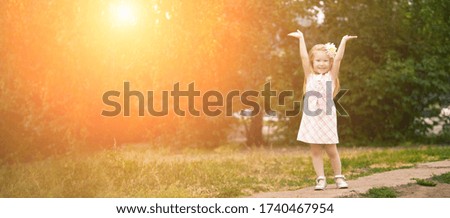 Beautiful little girl smiling. Look at the camera. Park outside the house. Advertising photo. Positive child after quarantine. End lockdown. Horizontal banner. Copyspace