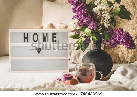 Sweet Home. Still life details in home interior of living room. Lilac flowers with hot cup tea. Cozy spring concept.