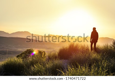 Anonymous silhouette of a man at mountain top against a foggy landscape. First man in another world. Concept of another planet discovering a new land. Copy space. Royalty-Free Stock Photo #1740471722