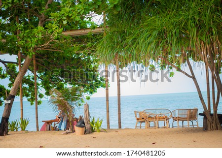 Relaxing chairs resting on the beach under a tree.