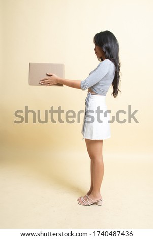 Delivery, relocation and unpacking.  young asian woman holding cardboard box   on beige background