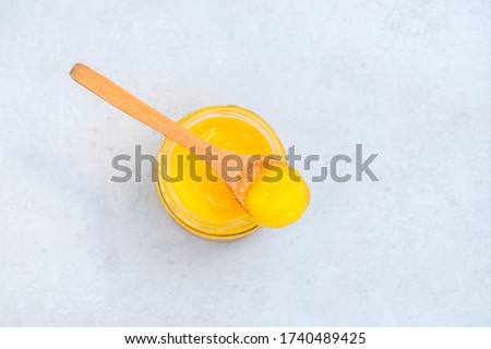 Jar of healthy ghee butter with spoon on neutral background with space for text Royalty-Free Stock Photo #1740489425
