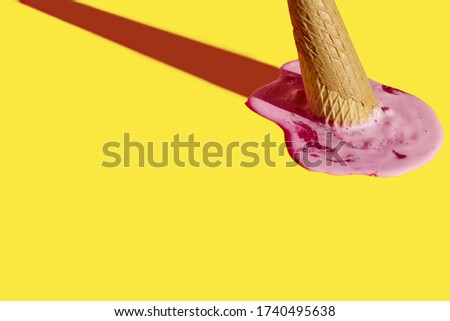 Strawberry ice cream cone upside down and melted. There's a yellow background behind it. Royalty-Free Stock Photo #1740495638