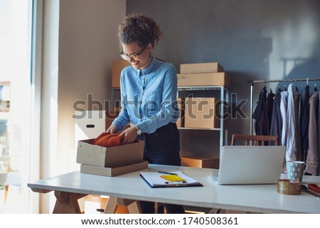 Small business owner. Women, owner of small business packing product in boxes preparing it for delivery.