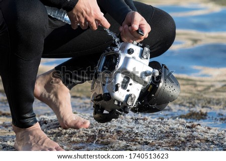 underwater photographer washing his scuba cam and scuba diving gear with water after an underwater shoot. Scuba cam or underwter camera with no logos in Mallorca beach.
