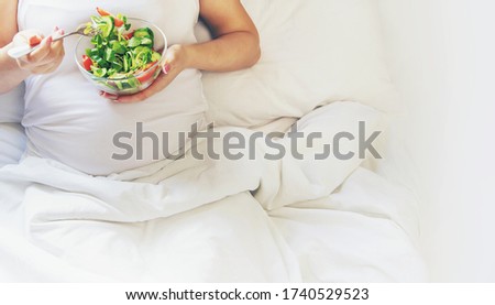 A pregnant woman eats a salad with vegetables. Selective focus. Food.