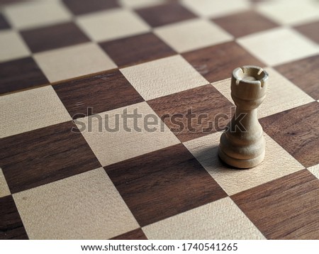 White Rook chess piece isolated on a wooden chess board. Strategic placement and play. Rich brown and white checkered board. Mind using boarding games with tactics and skills. Royalty-Free Stock Photo #1740541265