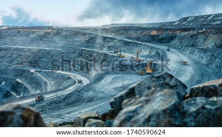 Work of trucks and the excavator in an open pit on gold mining, soft focus Royalty-Free Stock Photo #1740590624