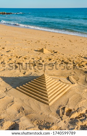 Artistic the Egyptian pyramid hand made on the sand beach sunny natural outdoors background. Art and craft concept