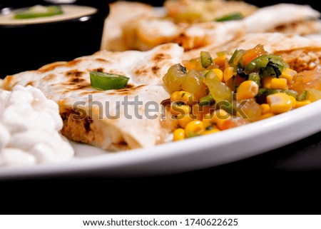 Mexican food, with delicious Mexican cuisine, 45º construction on black background. Nachos, burritos, guacamole, tacos, chilli etc.