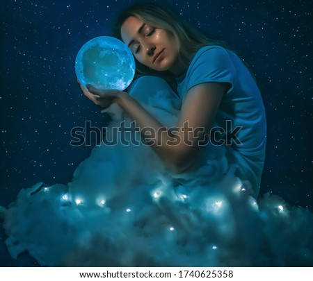 Young pretty woman with the full moon and clouds on the starryt blue background closeup.Art processing