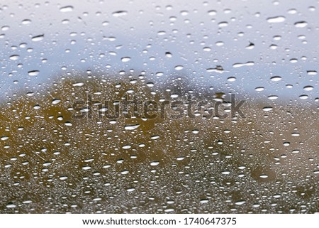 Drops Of Rain On the glass  on a rainy day with stormy sky.  Rainy abstract backdrop. Rainy weather.