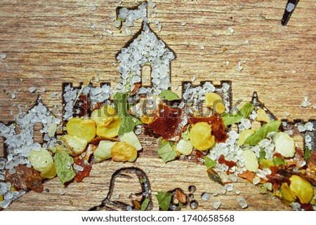 close-up still life with sea salt and dried hot spices sprinkled on a wooden stand with a burnt out castle silhouette. view from above